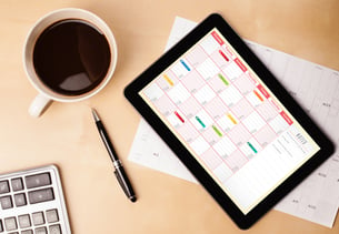 Workplace with tablet pc showing calendar and a cup of coffee on a wooden work table close-up-1